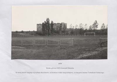 zdjęcie okładki Boisko główne GKS Grunwald Halemba. Po lewej stronie znajduje się trybuna dla kibiców, za boiskiem widać nasyp kolejowy, za nasypem internat Technikum Górniczego